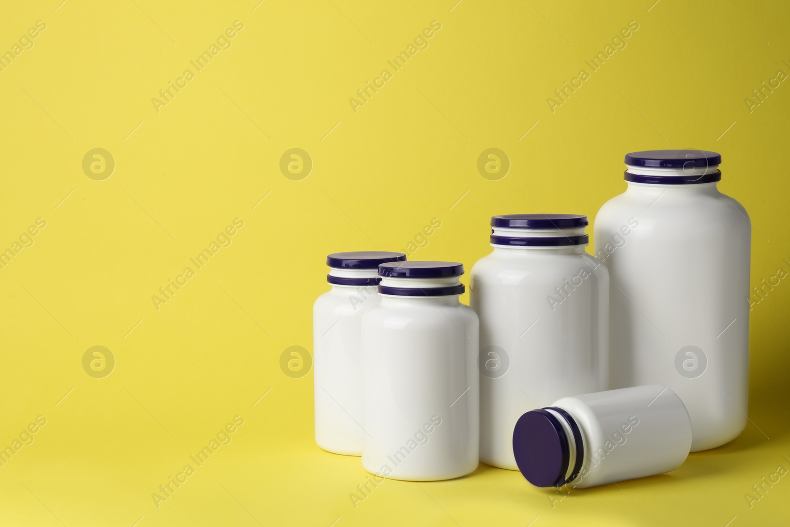Photo of Many medicine bottles on yellow background, space for text