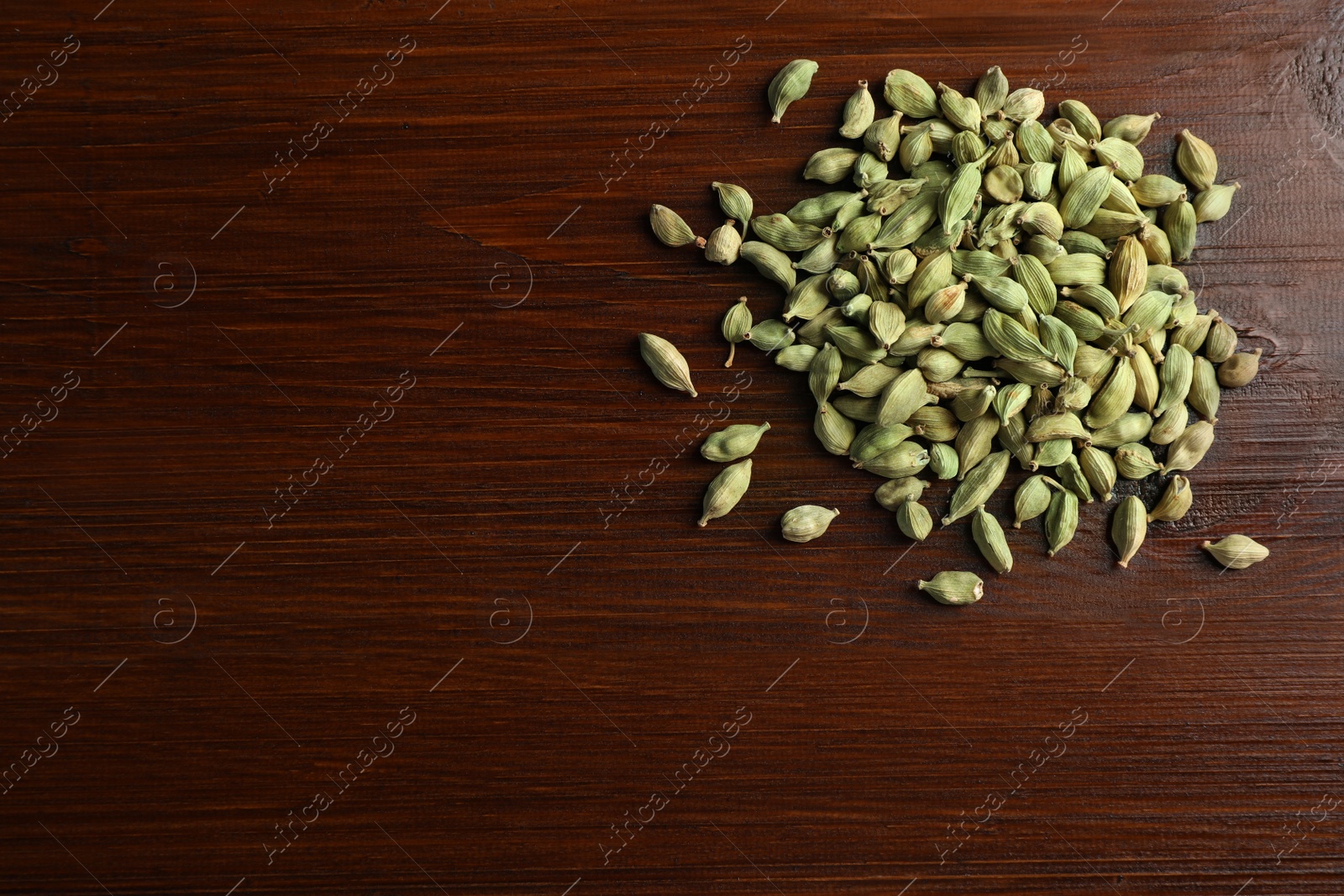 Photo of Pile of dry cardamom pods on wooden table, top view. Space for text