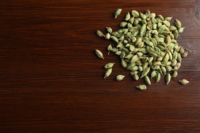 Pile of dry cardamom pods on wooden table, top view. Space for text