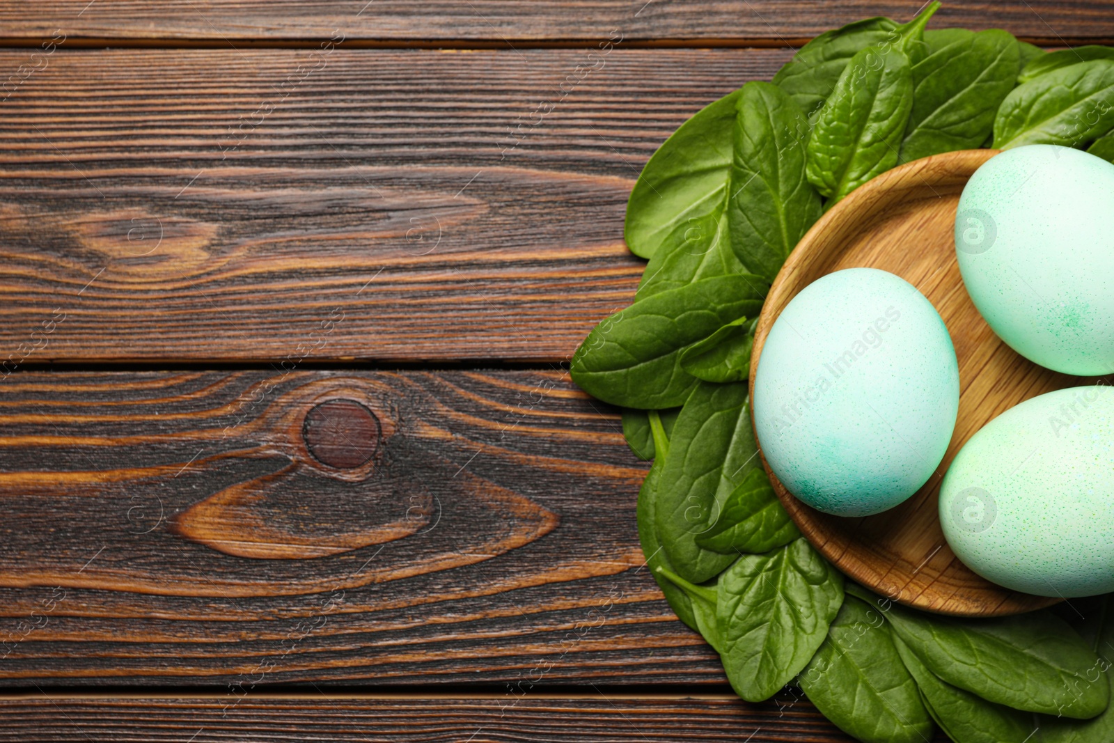 Photo of Naturally painted Easter eggs and space for text on wooden table, flat lay. Spinach used for coloring