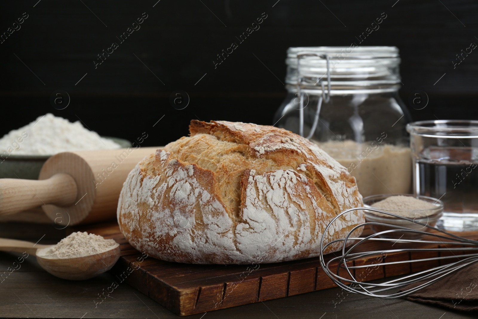 Photo of Freshly baked sourdough bread and ingredients on wooden table