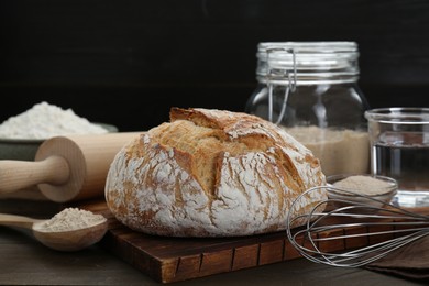 Photo of Freshly baked sourdough bread and ingredients on wooden table