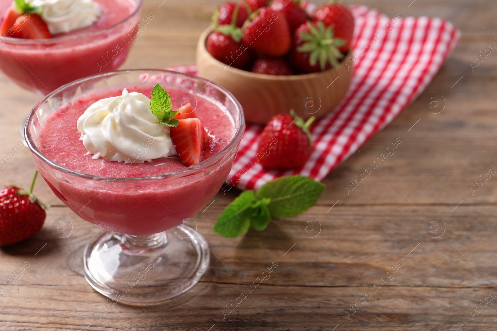 Photo of Delicious strawberry mousse with mint on wooden table, space for text