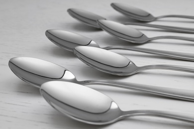 Photo of Clean empty table spoons on white wooden background