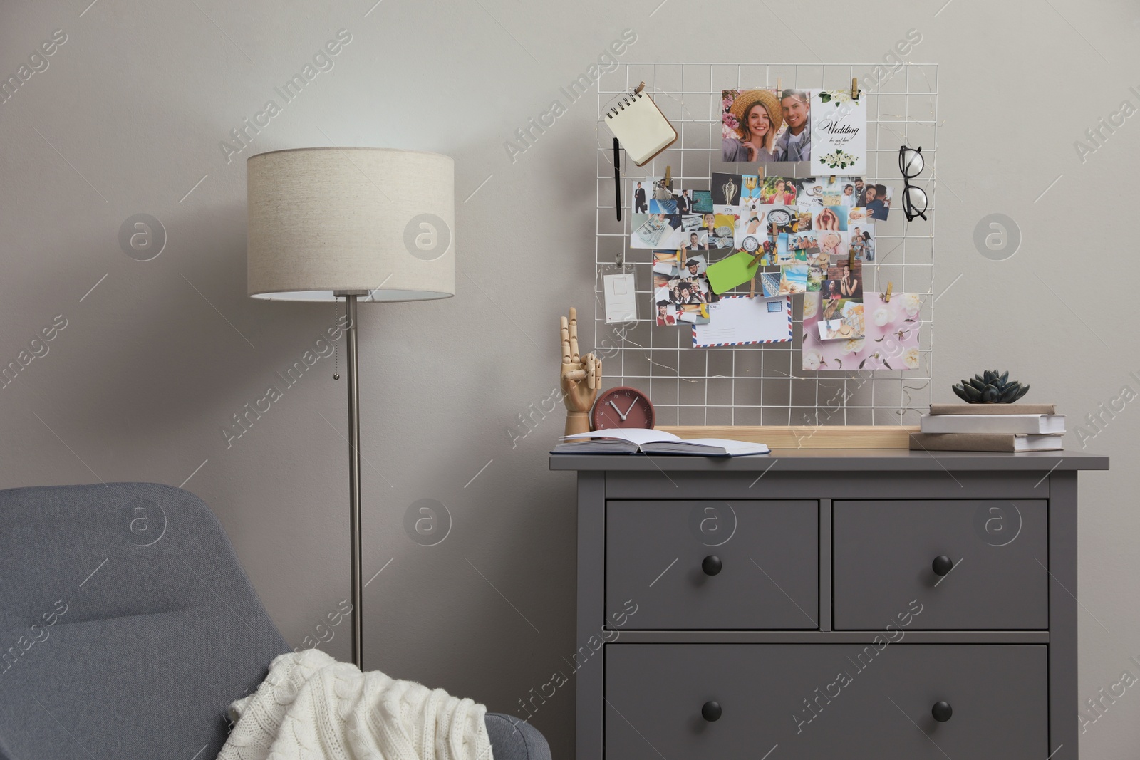 Photo of Stylish room interior with vision board, armchair and chest of drawers