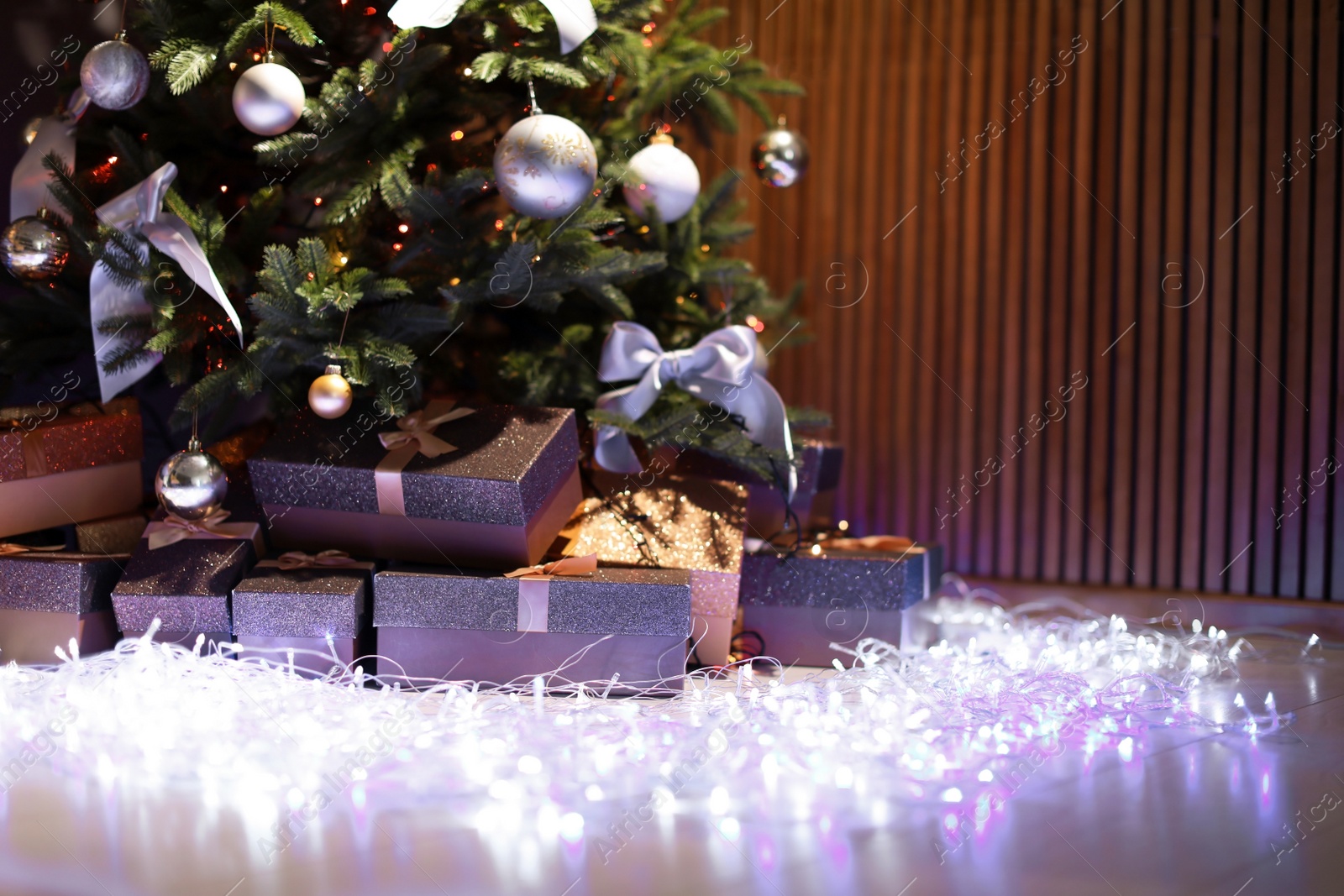 Photo of Beautiful Christmas tree, fairy lights and gift boxes indoors