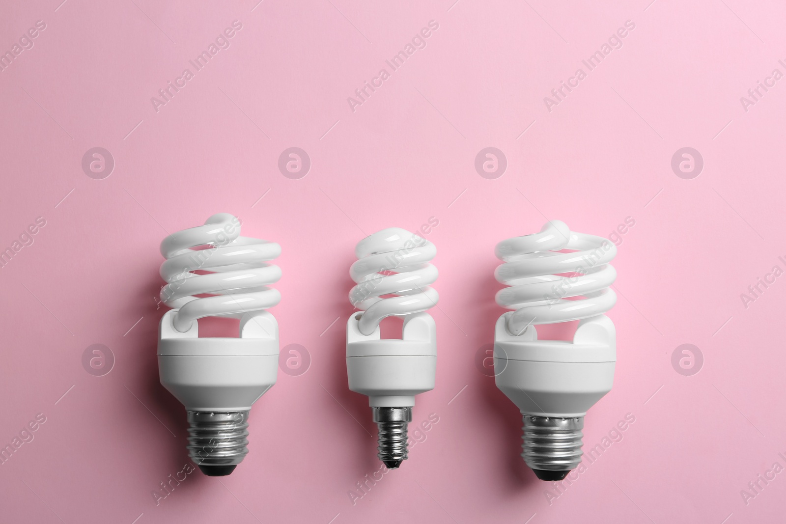 Photo of New fluorescent lamp bulbs on pink background, top view