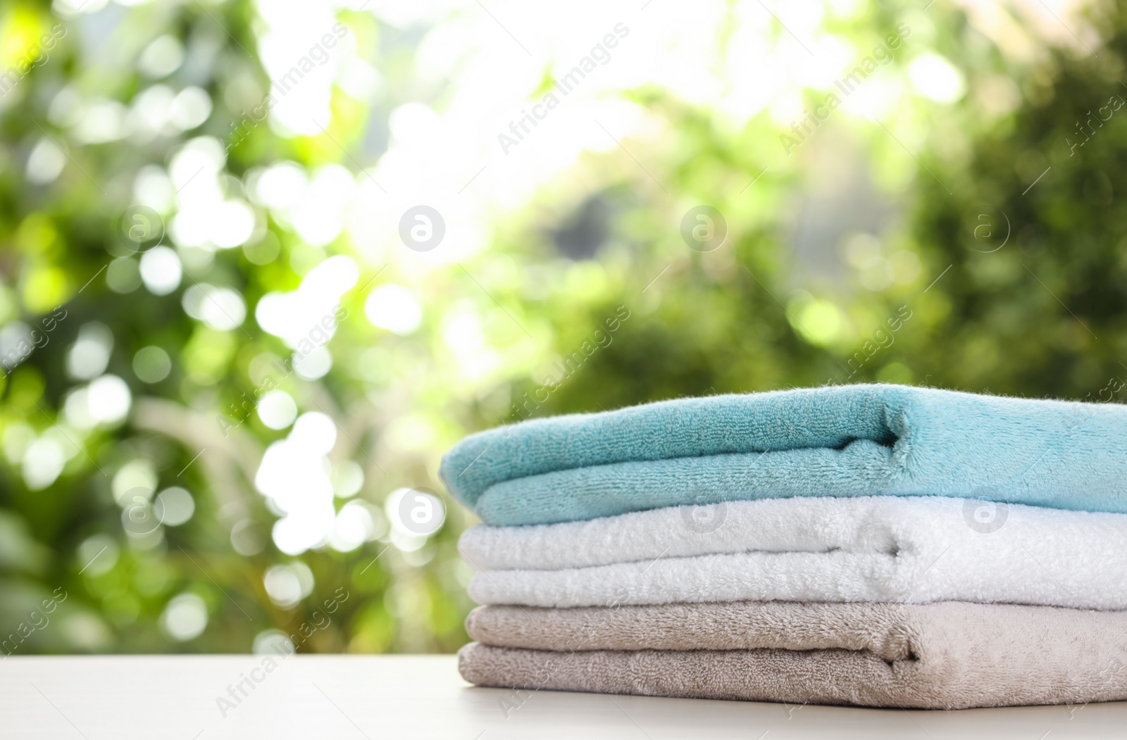 Photo of Stack of clean soft towels on table against blurred background. Space for text