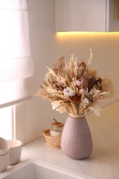 Bouquet of dry flowers and leaves on countertop in kitchen