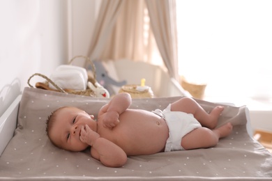 Photo of Cute little baby on changing table in room