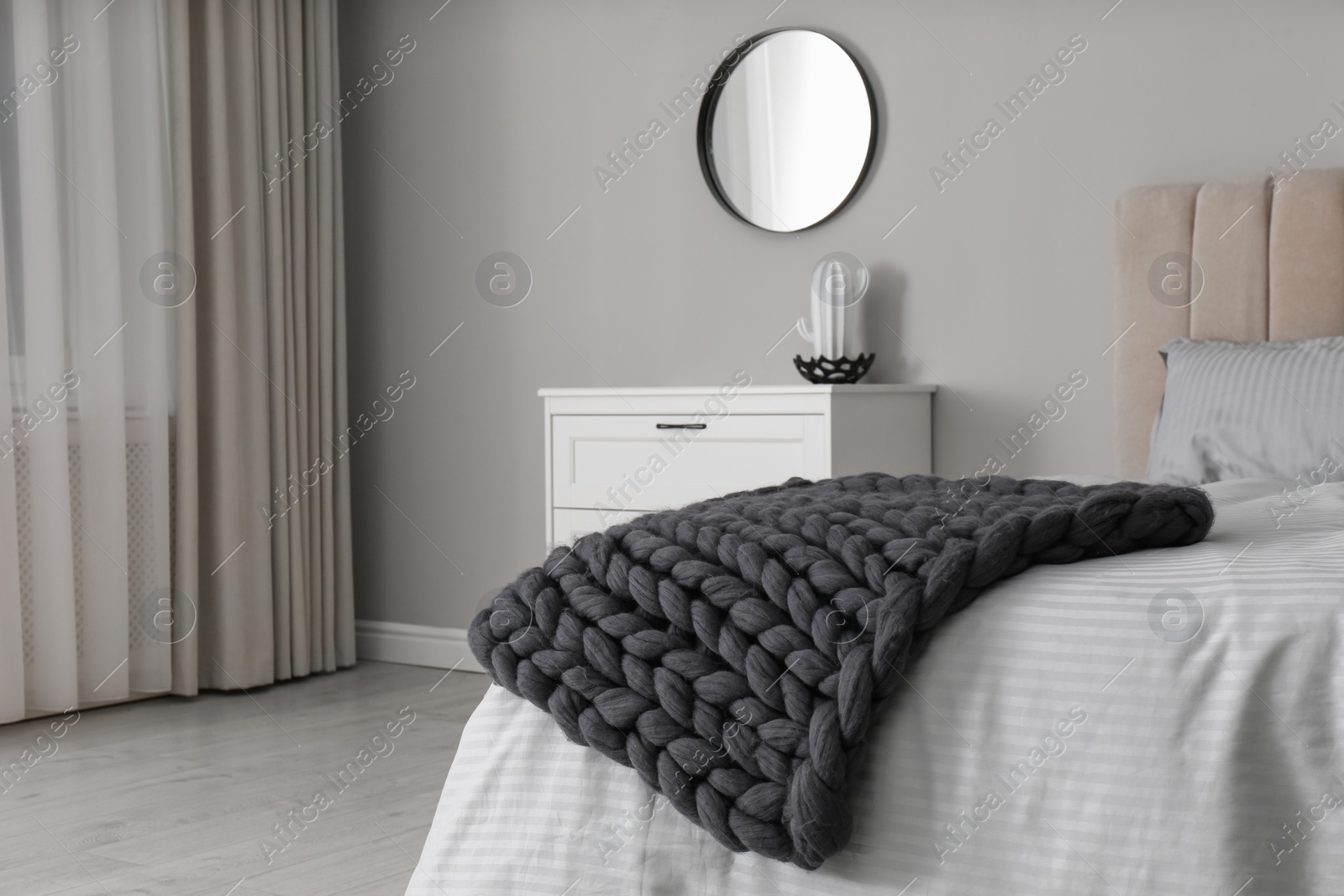Photo of Knitted merino wool plaid on bed in room