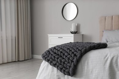 Knitted merino wool plaid on bed in room