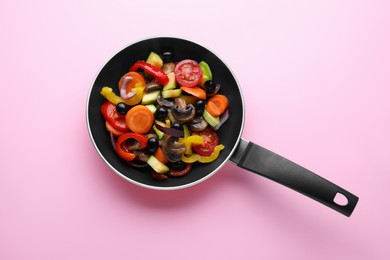 Photo of Mix of tasty vegetables in pan on pink background, top view
