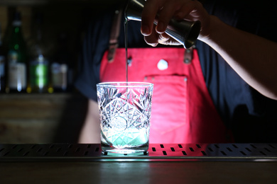 Photo of Bartender preparing fresh alcoholic cocktail at bar counter, closeup