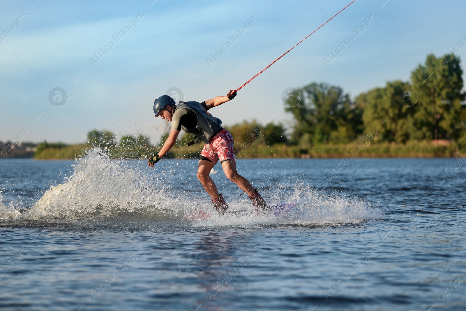 Photo of Teenage boy wakeboarding on river. Extreme water sport