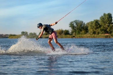 Teenage boy wakeboarding on river. Extreme water sport