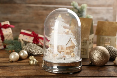 Beautiful Christmas snow globe and festive decor on wooden table