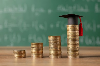 Photo of Scholarship concept. Graduation cap and stacked coins on wooden table