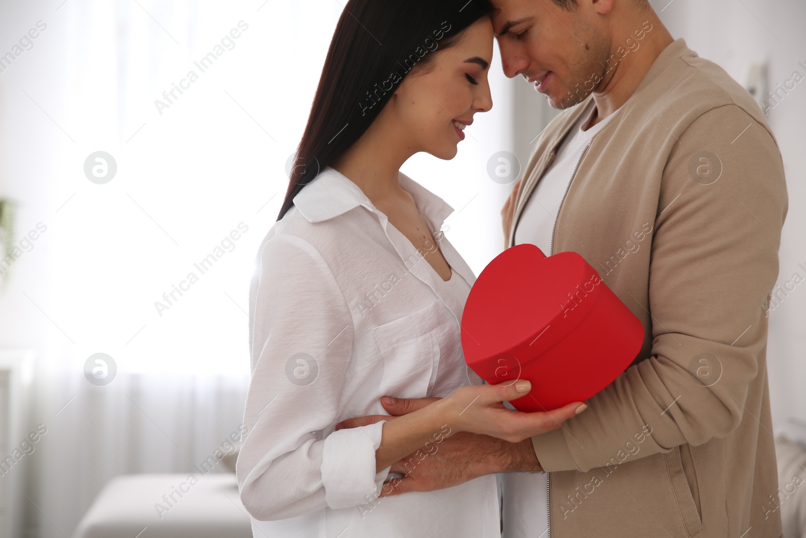 Photo of Lovely couple with gift box at home. Valentine's day celebration