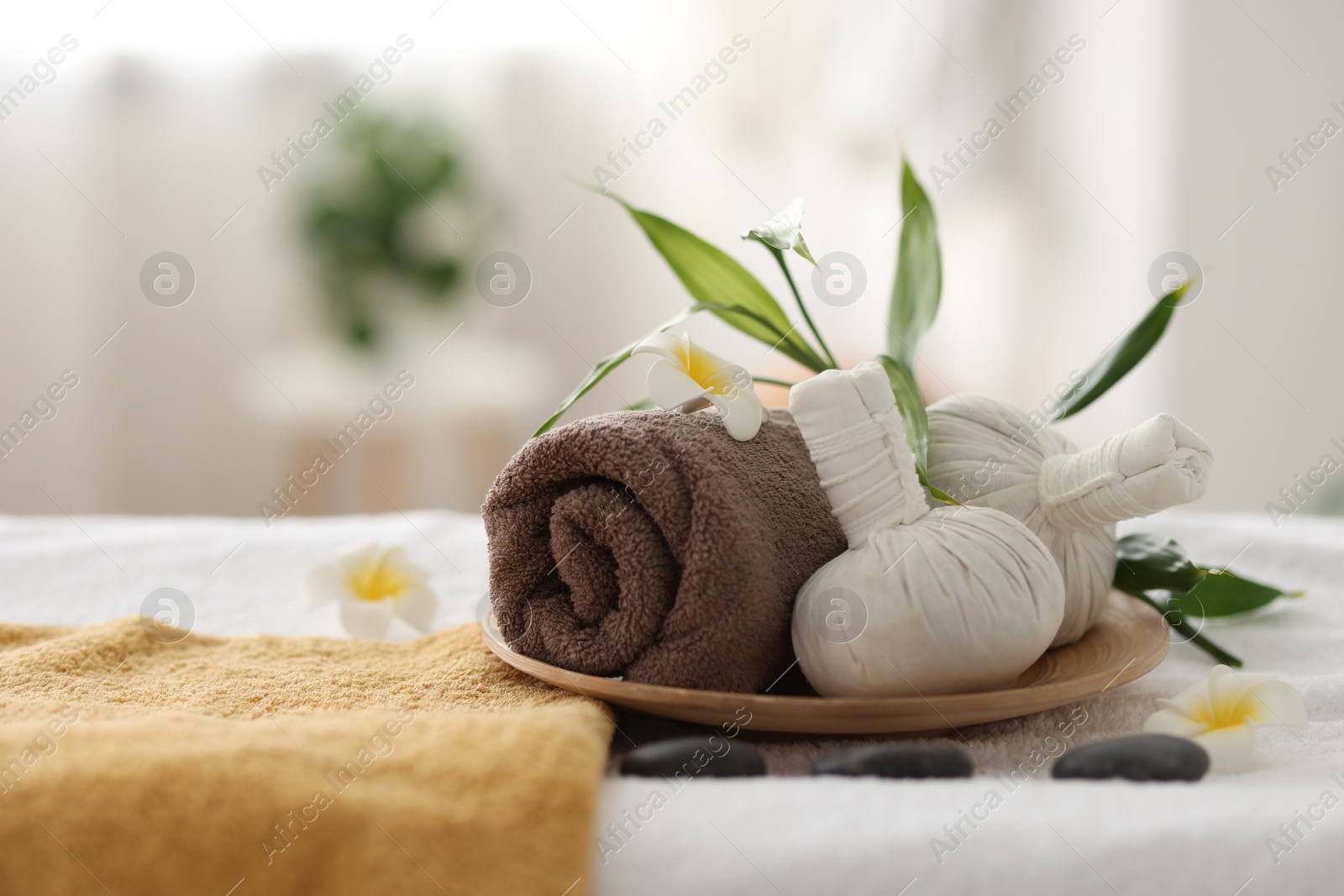 Photo of Spa stones, flowers and herbal bags on towel indoors