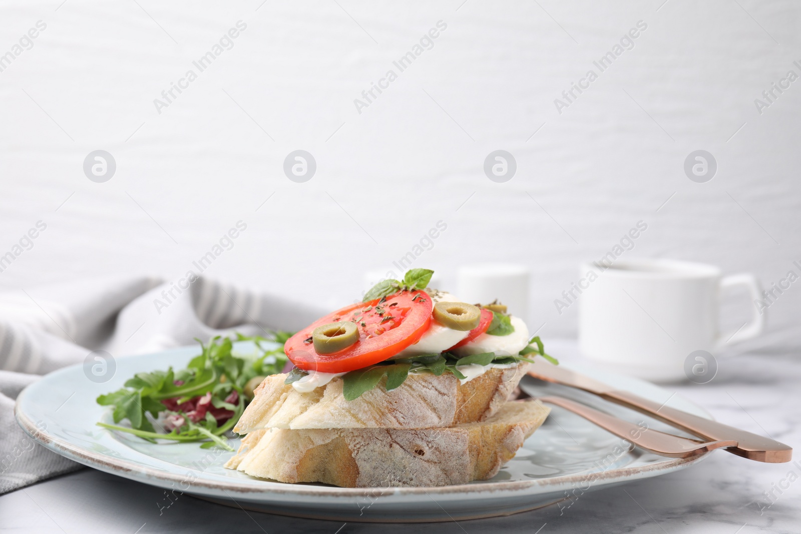 Photo of Tasty bruschetta with tomatoes, mozzarella and olives served on white marble table, closeup