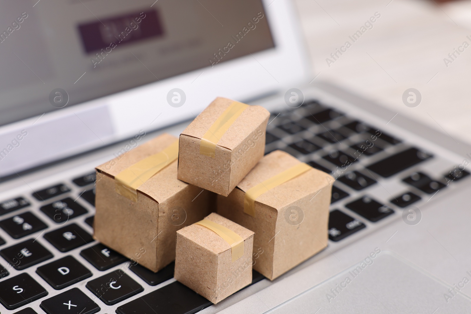 Photo of Internet shopping. Small cardboard boxes on laptop, closeup