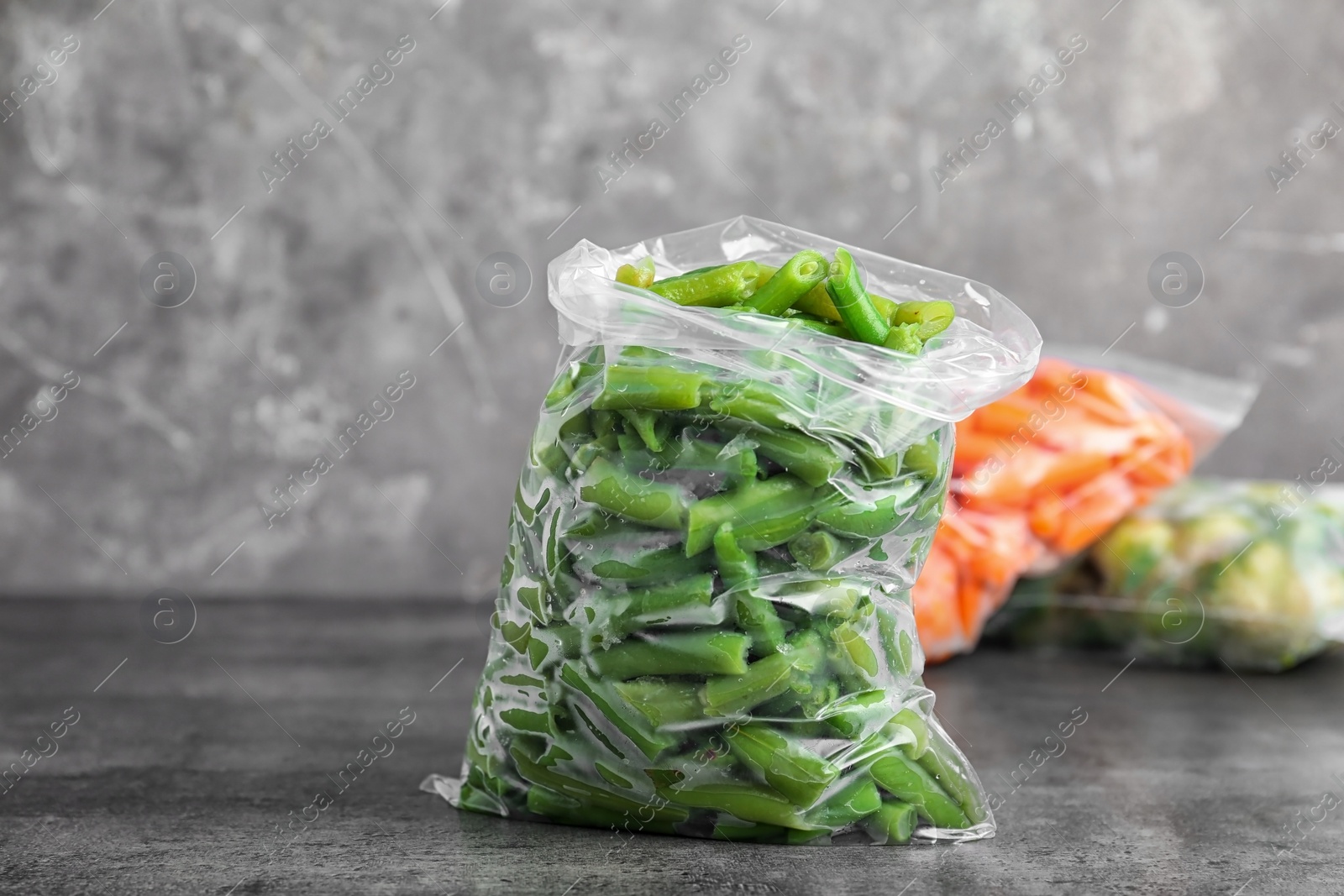 Photo of Plastic bag with frozen green beans on table. Vegetable preservation