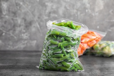 Photo of Plastic bag with frozen green beans on table. Vegetable preservation