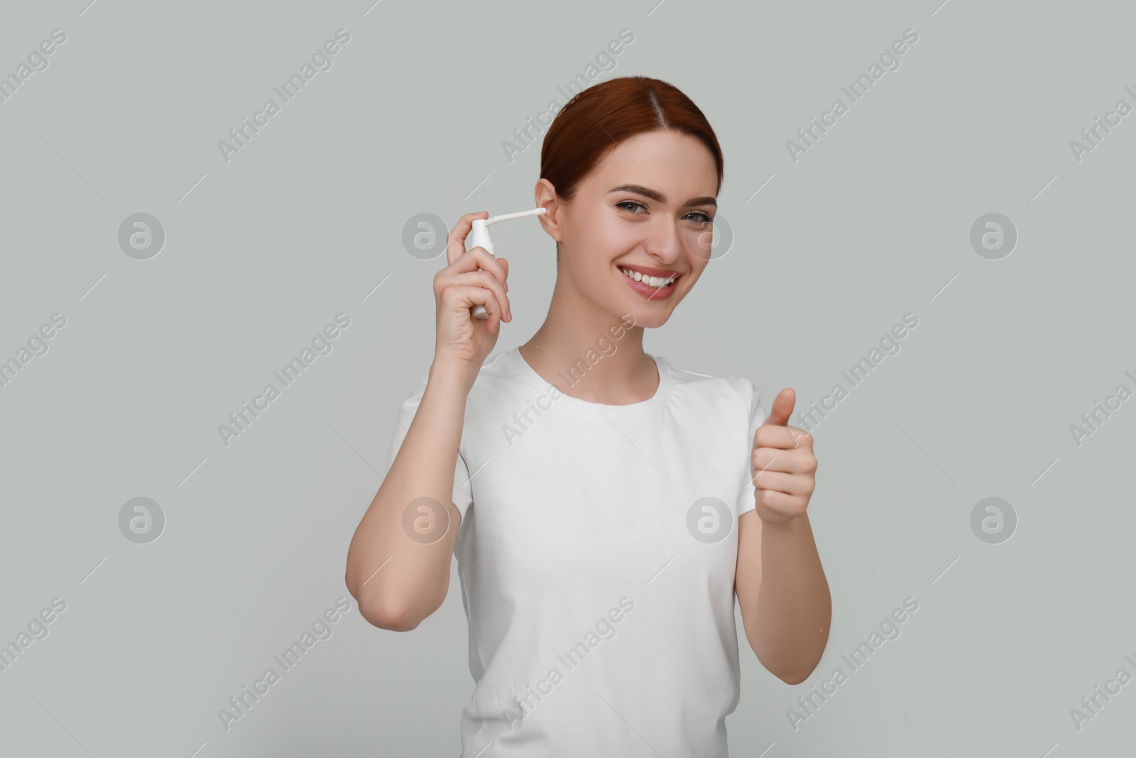 Photo of Woman using ear spray on light grey background