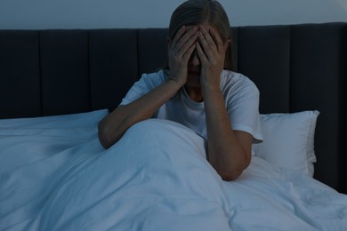 Woman suffering from headache in bed at night