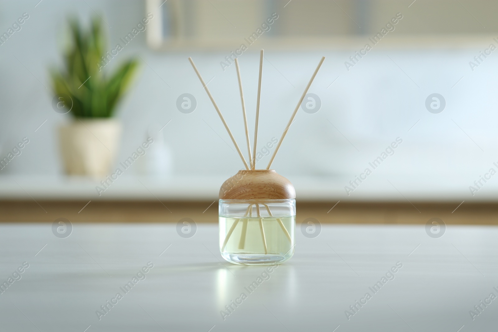 Photo of Aromatic reed air freshener on table indoors