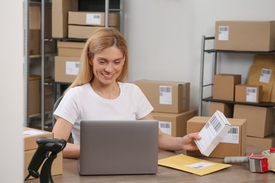 Photo of Seller with parcels and laptop in office. Online store