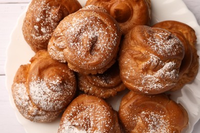 Photo of Delicious profiteroles with powdered sugar on white table, top view