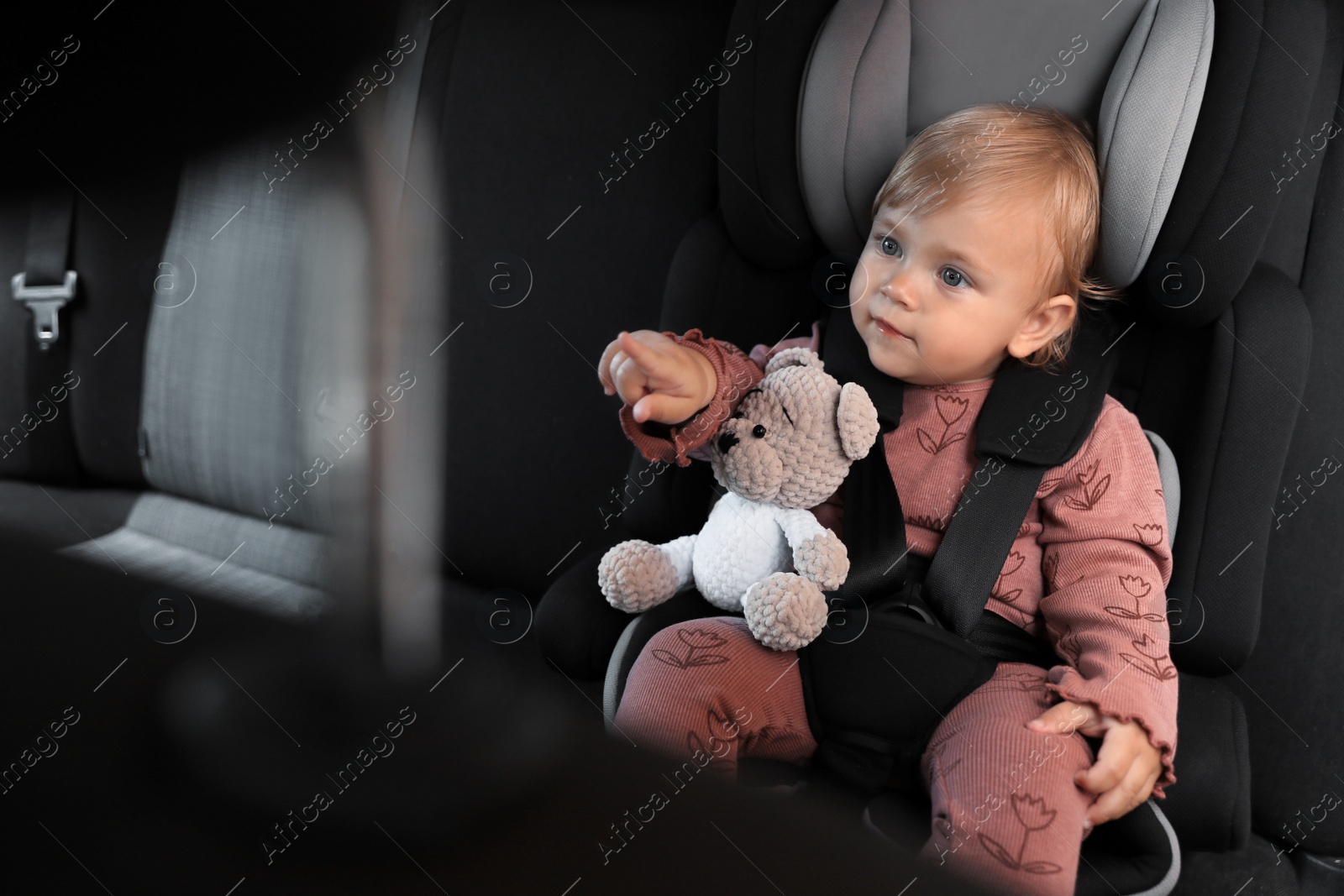 Photo of Cute little girl sitting in child safety seat inside car