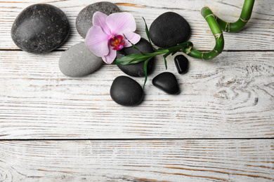Photo of Stones, bamboo, orchid flower and space for text on wooden background, flat lay. Zen lifestyle