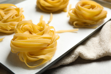 Raw tagliatelle pasta in baking pan, closeup view