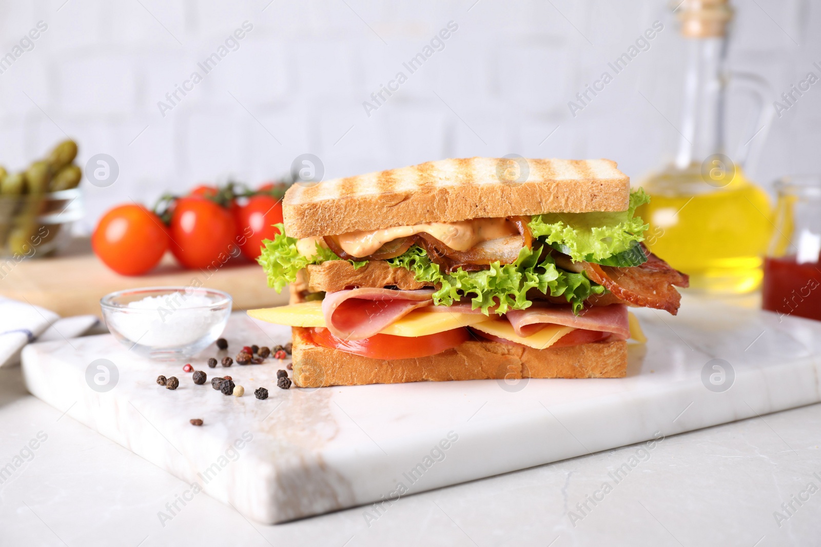 Photo of Tasty sandwich with ham and bacon served on light table