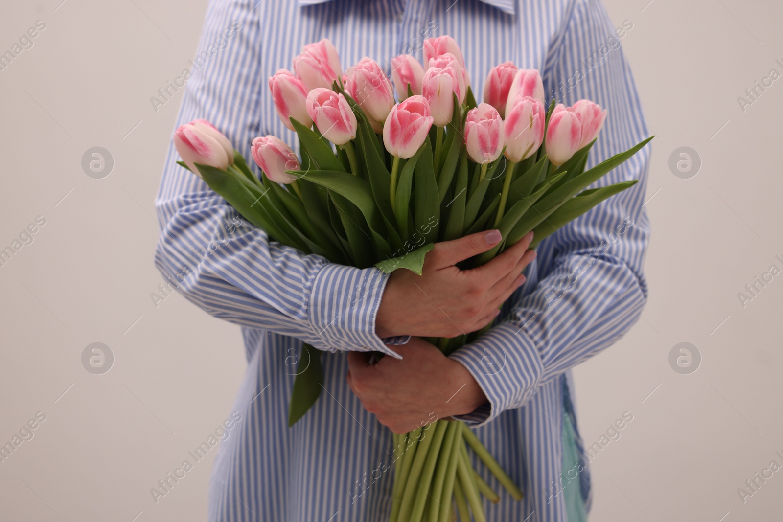 Photo of Woman with bouquet of beautiful fresh tulips on light grey background, closeup