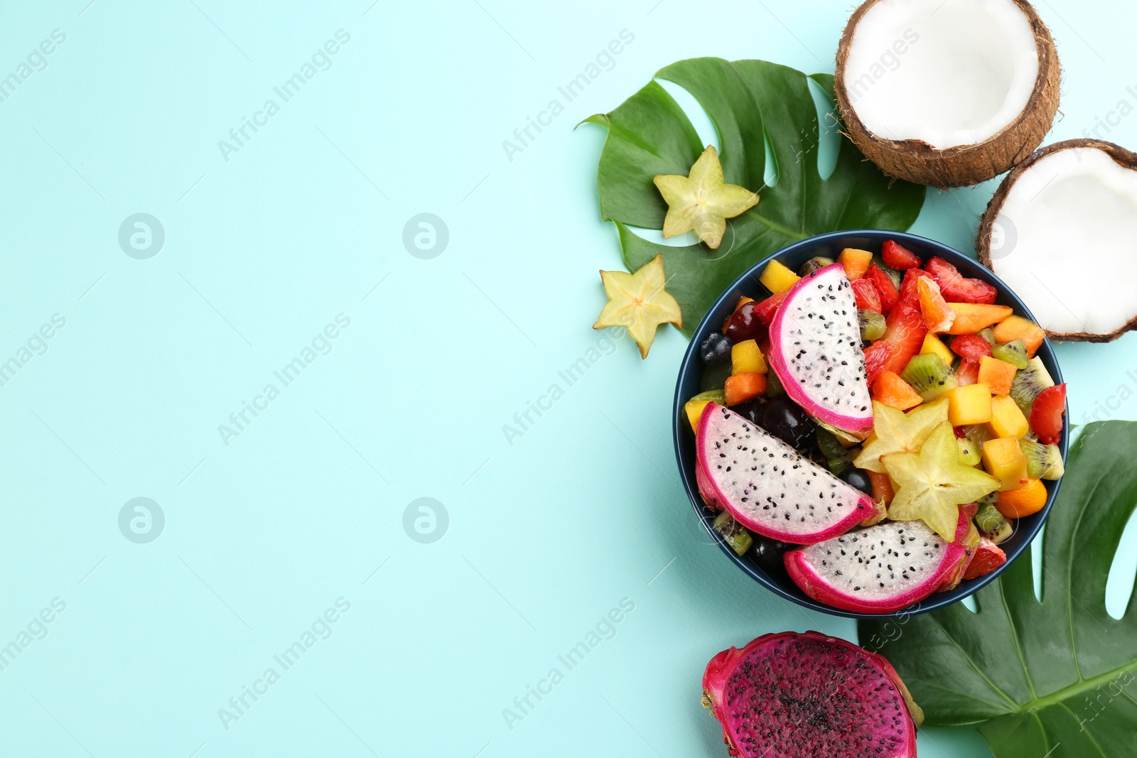 Photo of Flat lay composition with delicious exotic fruit salad on turquoise background. Space for text