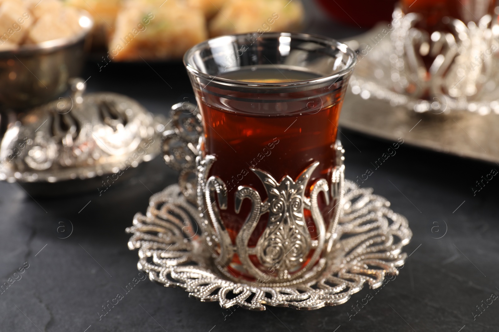 Photo of Traditional Turkish tea served in vintage tea set on black table, closeup