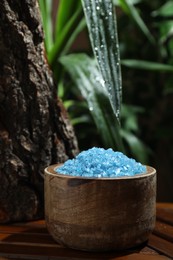 Photo of Bowl of blue sea salt on wooden table, closeup. Space for text