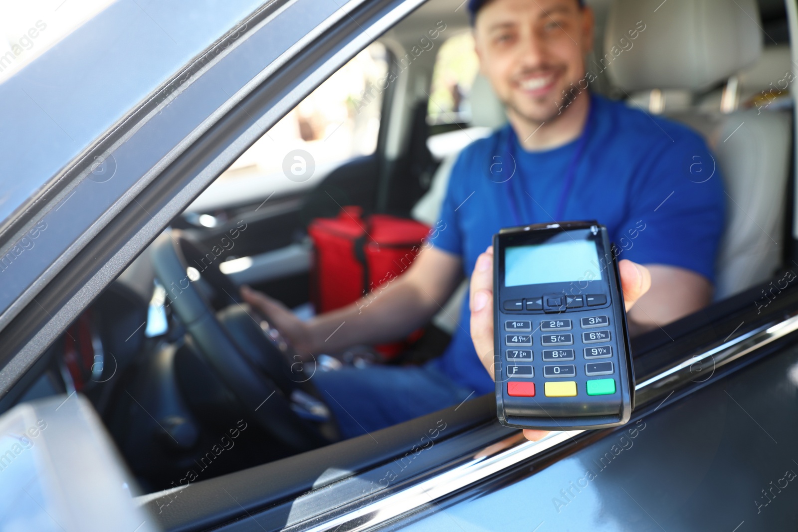 Photo of Male courier with terminal in car. Food delivery service