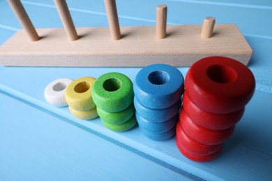 Photo of Stacking and counting game pieces on light blue wooden table, closeup. Motor skills development
