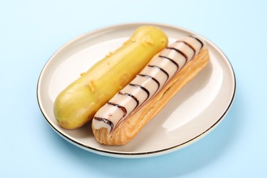 Photo of Delicious eclairs covered with glaze on light blue background