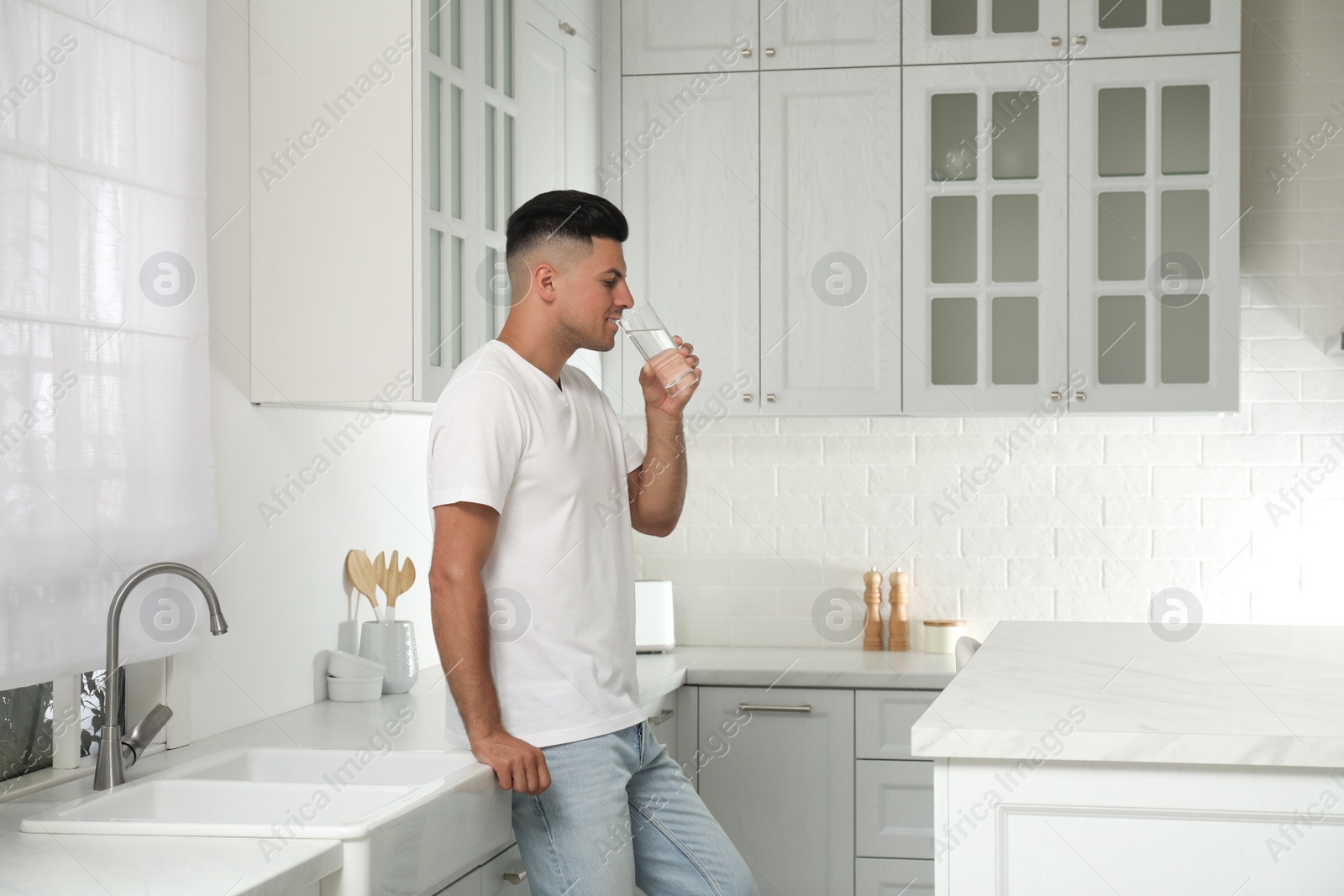 Photo of Man drinking tap water from glass in kitchen