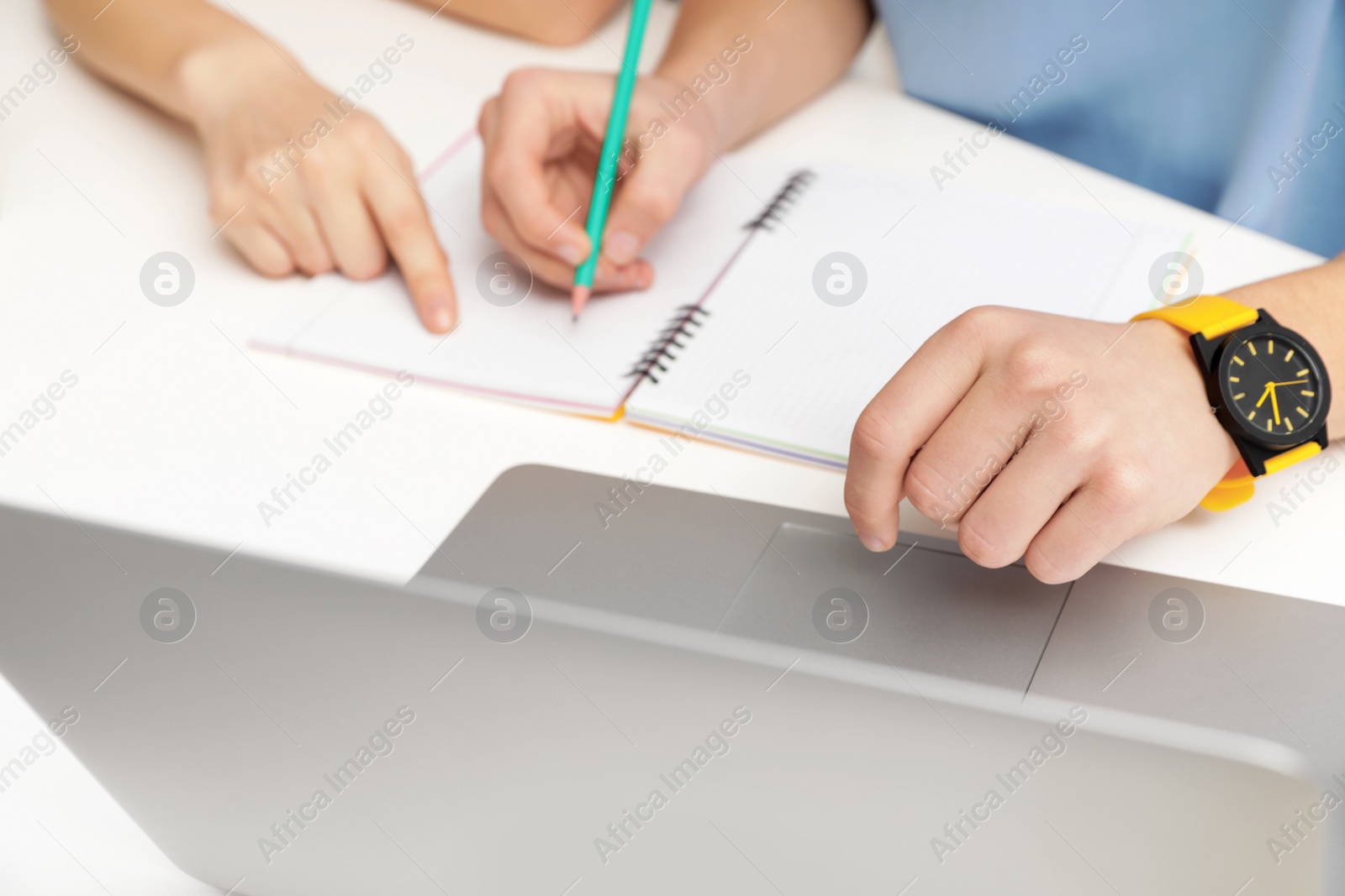 Photo of Mother helping her teenager son with homework at desk, closeup