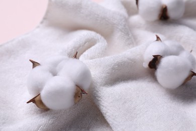 Photo of Fluffy cotton flowers on white terry towel, closeup