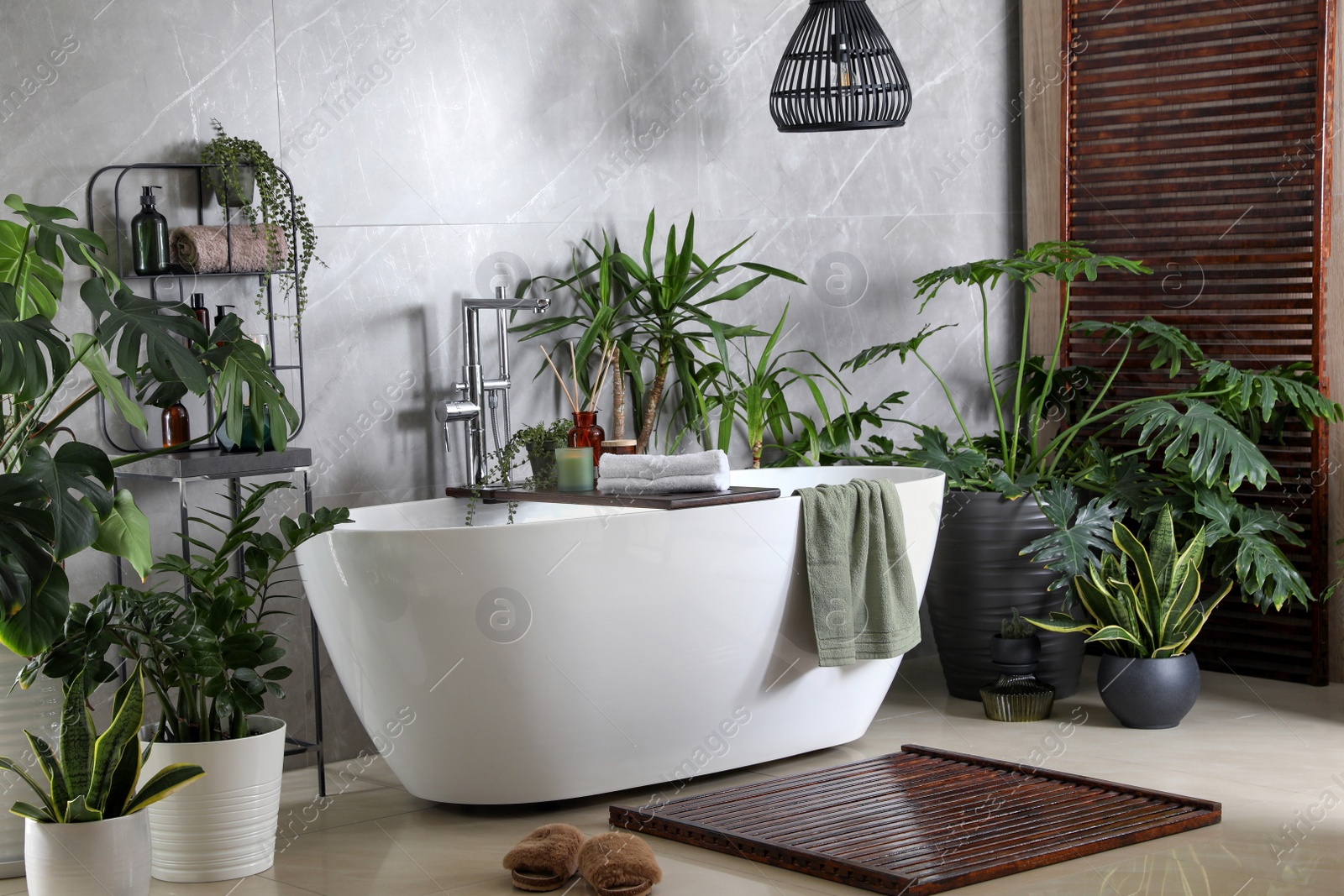 Photo of Modern white tub and beautiful green houseplants in bathroom. Interior design