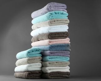 Photo of Different fresh soft terry towels on grey background