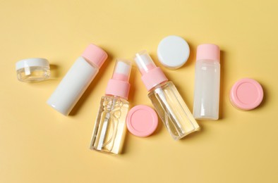 Photo of Cosmetic travel kit. Small containers of personal care products on yellow background, flat lay